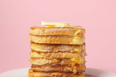 eggy bread on a pink background. Butter melts on a stack of eggy breads. Tasty breakfast.