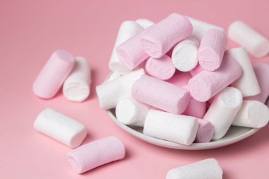 Pembe arka planda şekerlemeler. Beyaz bir tabakta renkli şekerlemeler. Tatlı çok lezzetli.