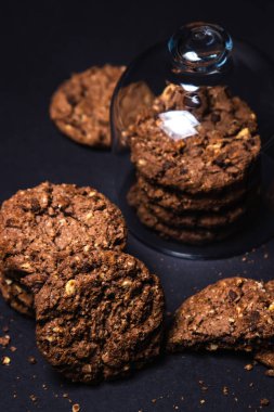 Siyah arka planda çikolata parçacıklı kurabiyeler. Tatlı çikolatalı şeker. Ev yapımı kurabiyeler
