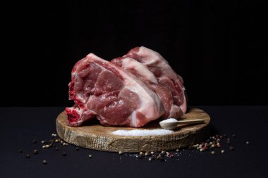 Siyah arka planda domuz eti. Tahtada kemikli et filetosu. Et pişirme