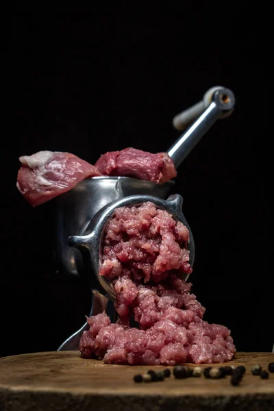 Meat in a meat grinder on a black background. Pork meat is twisted in an old meat grinder. meat cooking.