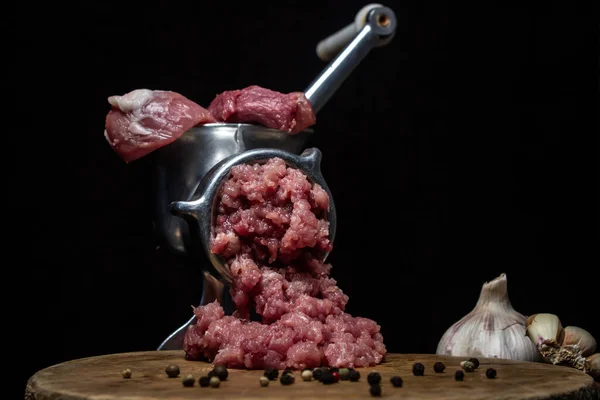 Meat in a meat grinder on a black background. Pork meat is twisted in an old meat grinder. meat cooking.