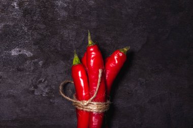 Siyah arka planda kırmızı biber. Acı biber bir demet bağlı. Olgun sebze