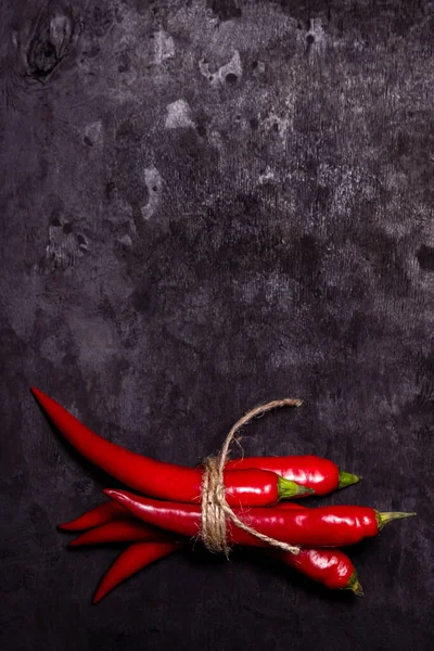 黒の背景に赤唐辛子 熱いコショウが束に結ばれた 熟した野菜 — ストック写真