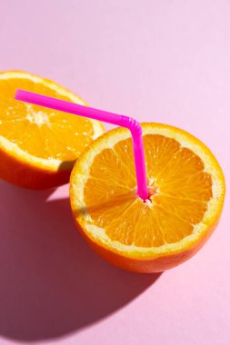 Taze doğal portakal suyu kavramı. Pembe arka planda dilimlenmiş turuncu. Serinletici içecek.