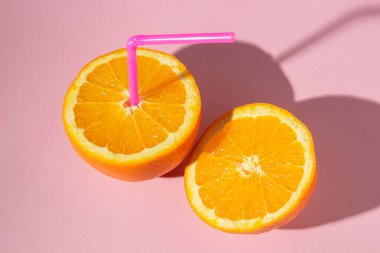 Taze doğal portakal suyu kavramı. Pembe arka planda dilimlenmiş turuncu. Serinletici içecek.