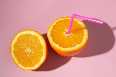 Taze doğal portakal suyu kavramı. Pembe arka planda dilimlenmiş turuncu. Serinletici içecek.