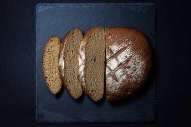 Siyah arka planda ekmek. Koyu bir tabakta ev yapımı taze ekmek. Geleneksel yemek.