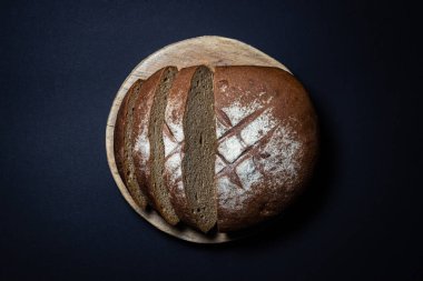 Siyah arka planda ekmek. Tahtada ev yapımı taze ekmek dilimlenmiş. Geleneksel yemek.