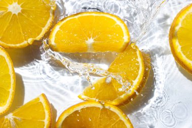 Beyaz arka planda portakal dilimleri. Portakal dilimleri suya düşer. Turunçgil meyvesi tazeleniyor