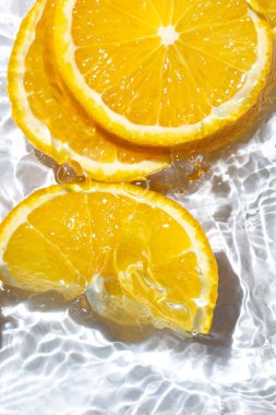 Beyaz arka planda portakal dilimleri. Portakal dilimleri suya düşer. Turunçgil meyvesi tazeleniyor