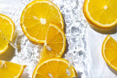 Beyaz arka planda portakal dilimleri. Portakal dilimleri suya düşer. Turunçgil meyvesi tazeleniyor