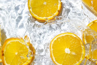 Beyaz arka planda portakal dilimleri. Portakal dilimleri suya düşer. Turunçgil meyvesi tazeleniyor