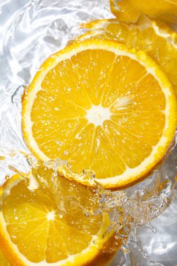 Beyaz arka planda portakal dilimleri. Portakal dilimleri suya düşer. Turunçgil meyvesi tazeleniyor