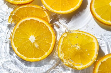 Beyaz arka planda portakal dilimleri. Portakal dilimleri suya düşer. Turunçgil meyvesi tazeleniyor