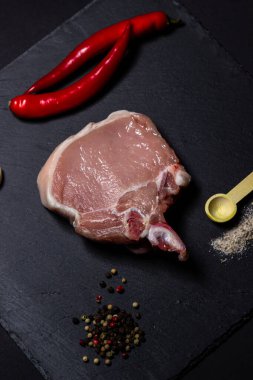 Siyah arka planda bir parça domuz eti. Koyu bir tabakta çiğ et. Taze ve taze et..