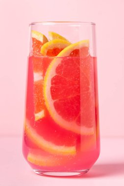 Pembe arka planda greyfurtlu pembe kokteyl. Tatlı meyve kokteyli. Lezzetli içecek