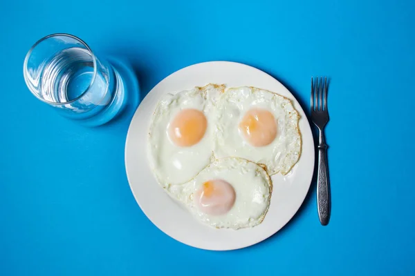 Stekta Ägg Blå Bakgrund Tre Stekta Ägg Tallrik Snabb Och — Stockfoto