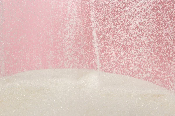 분홍색 배경의 설탕을 무더기의 설탕에 뿌리는 것이다 — 스톡 사진