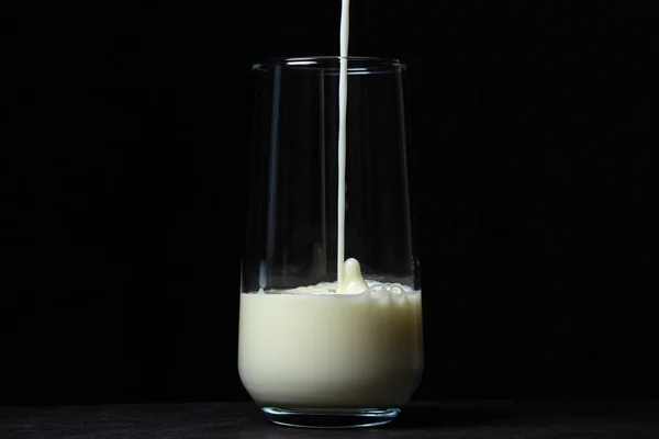 黑色背景的牛奶杯 牛奶倒入透明的玻璃杯中 天然健康饮品 — 图库照片