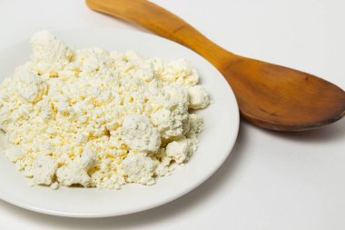 Beyaz arka planda bir tabak süzme peynir. Sağlıklı ve lezzetli süt ürünleri.