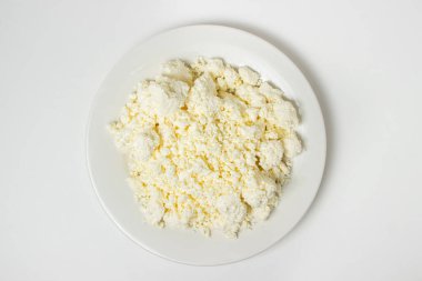 Beyaz arka planda bir tabak süzme peynir. Sağlıklı ve lezzetli süt ürünleri.