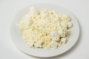 Beyaz arka planda bir tabak süzme peynir. Sağlıklı ve lezzetli süt ürünleri.