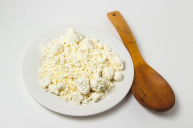 Beyaz arka planda bir tabak süzme peynir. Sağlıklı ve lezzetli süt ürünleri.