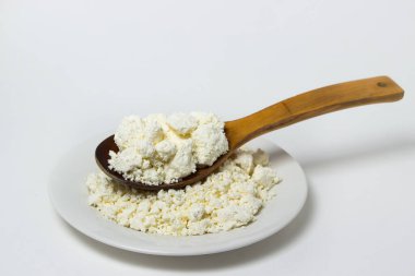 Beyaz arka planda bir tabak süzme peynir. Sağlıklı ve lezzetli süt ürünleri.