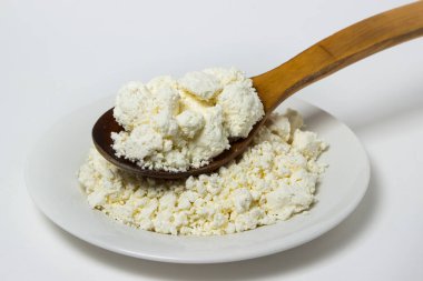 Beyaz arka planda bir tabak süzme peynir. Sağlıklı ve lezzetli süt ürünleri.