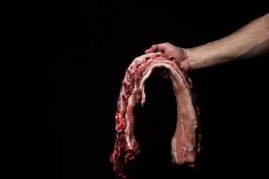 Siyah arka planda çiğ domuz pirzolası. Elim taze domuz eti tutuyor..