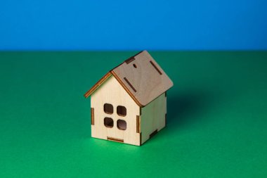 Renkli arka planda küçük tahta bir oyuncak ev. Emlak alım ve satım konsepti. Emlak hizmetleri