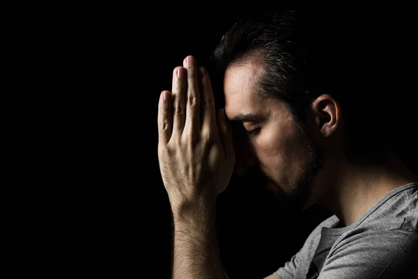 Siyah arka planda ellerini Tanrı 'ya dua etmek için kavuşturan adam. Tanrı 'ya mutluluk ve daha iyi bir hayat için dua et. Günahlarından tövbe et. Tanrı 'yla birlik