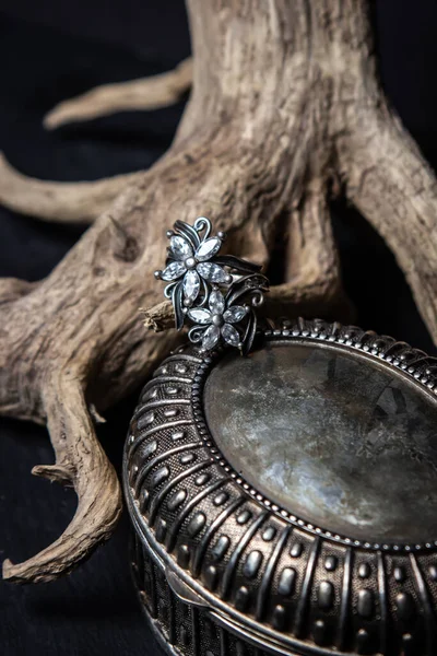 黑色背景上木制树枝上的银戒指 漂亮女人的饰物 — 图库照片