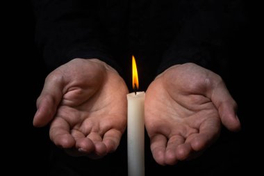 Siyah arka planda yanan bir mumun yanında. Yanan bir mum, hatıra ve kederin işaretidir. Küçük mum ateşi