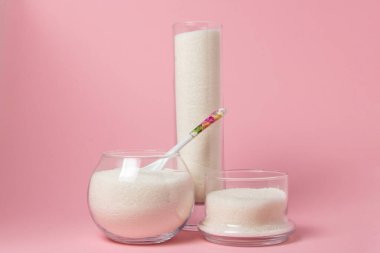 Pembe arka planda şeker. Farklı cam kaplarda şeker. Şeker rezervleri