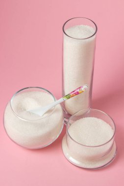 Pembe arka planda şeker. Farklı cam kaplarda şeker. Şeker rezervleri