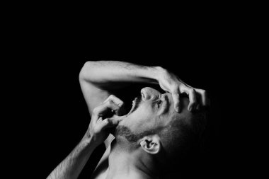 Bir adam ellerini siyah bir arka planda tutarak deliler gibi çığlık atıyor. Sinir krizi. Açık bir duygu gösterisi..