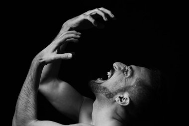 Siyah arka planda öfkeyle bağıran bir adam. Açık bir duygu gösterisi. Sinir krizi.