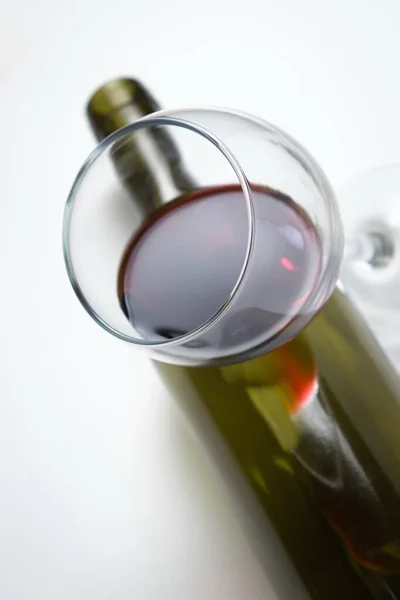 Ένα Ποτήρι Κόκκινο Κρασί Ένα Άδειο Μπουκάλι Λευκό Φόντο Υπερβολική — Φωτογραφία Αρχείου