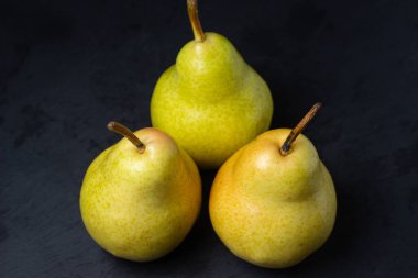 Siyah arka planda armutlar. Olgun sarı armutlar. Sulu ve taze meyveler