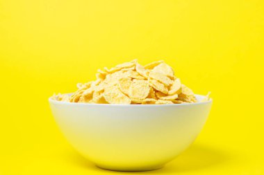 Corn flakes on a yellow background. Useful and tasty breakfast. Diet food
