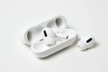 Beyaz arka planda beyaz kablosuz kulaklıklar. Çantalı modern kablosuz kulaklıklar