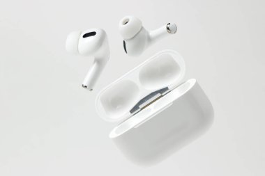 Beyaz arka planda beyaz kablosuz kulaklıklar. Çantalı modern kablosuz kulaklıklar