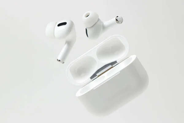 Beyaz arka planda beyaz kablosuz kulaklıklar. Çantalı modern kablosuz kulaklıklar