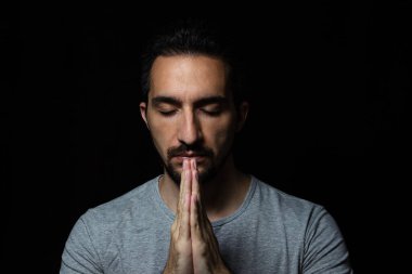 Siyah arka planda ellerini Tanrı 'ya dua etmek için kavuşturan adam. Tanrı 'ya mutluluk ve daha iyi bir hayat için dua et. Günahlarından tövbe et. Tanrı 'yla birlik