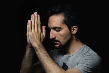 Siyah arka planda ellerini Tanrı 'ya dua etmek için kavuşturan adam. Tanrı 'ya mutluluk ve daha iyi bir hayat için dua et. Günahlarından tövbe et. Tanrı 'yla birlik