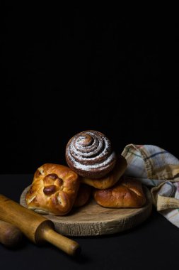 Siyah arka planda çörekler. Bir demet ev yapımı çörek. Lezzetli kahvaltı.