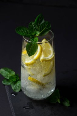 Siyah arka planda taze bir kokteyl. Buzlu ve limonlu meşrubat. Soğuk içecek.