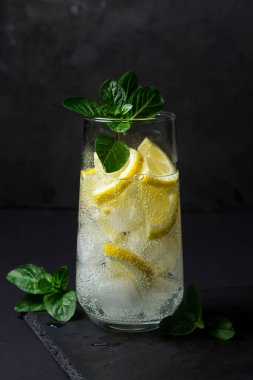 Siyah arka planda taze bir kokteyl. Buzlu ve limonlu meşrubat. Soğuk içecek.